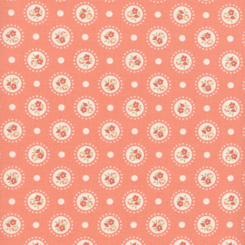 Coral pink fabric with medallions of red flowers on a polka dotted background.