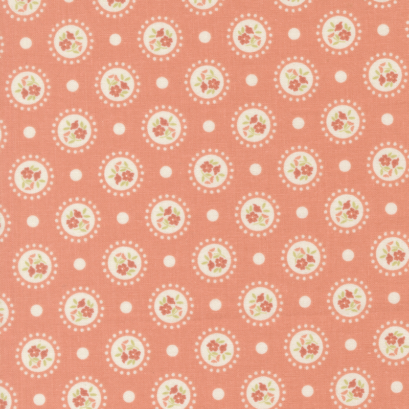 Coral pink fabric with medallions of red flowers on a polka dotted background.