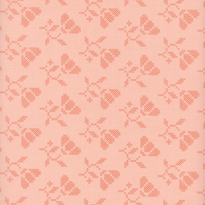 Tonal pink fabric with cross-stitched flowers.