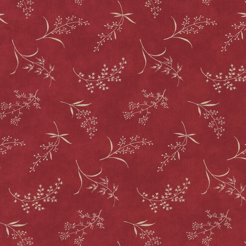 Fabric pattern of ditsy leaves and flowers on a red background.