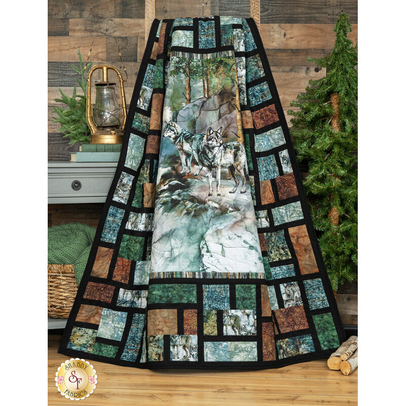 A shot of the panel quilt artistically draped over a wooden ladder to show dimension and movement. Coordinating forest and camping decor sits behind the quilt.