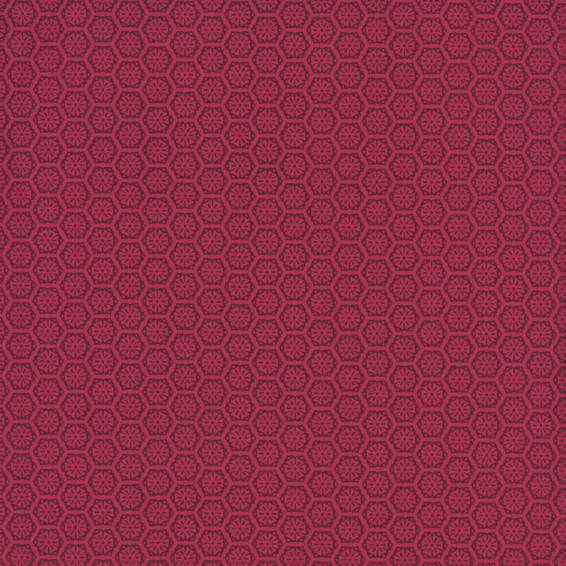 A bright pink fabric with a tonal pattern of tiled geometric emblems.