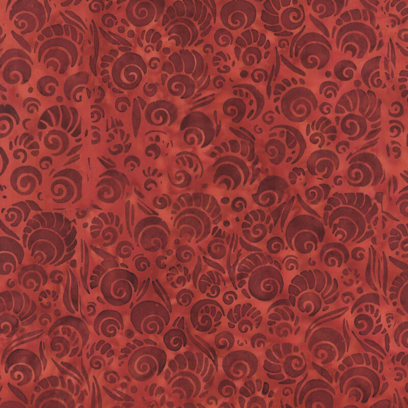 Mottled red batik fabric with darker tonal swirls with designs to make them look like shells.