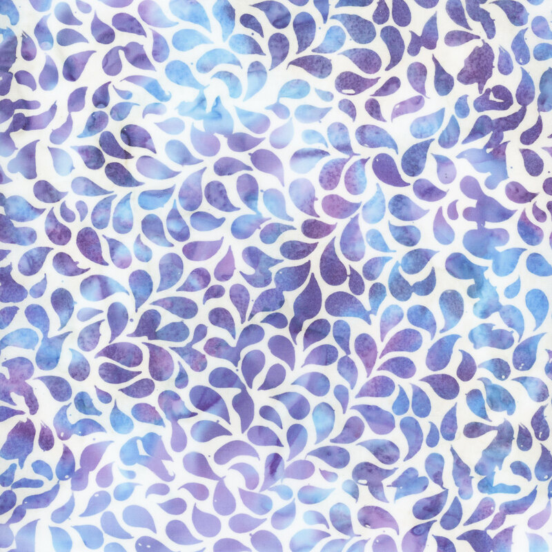 Mottled batik fabric with blue and purple teardrop shapes tossed on a white fabric.