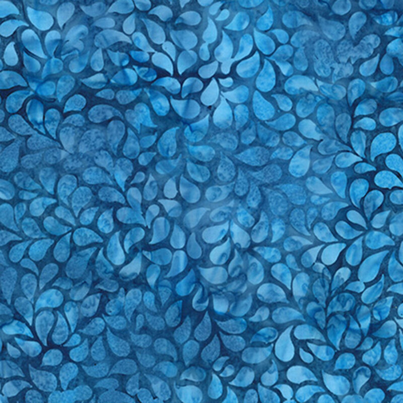 Mottled batik fabric with blue and aqua petals tossed on a dark blue fabric.
