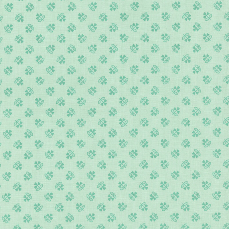 Mint green fabric with a tonal ditsy pattern of stylized clovers.