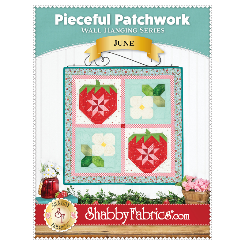Front cover of the pattern showing the finished June wall hanging in bright red, blue, green, and white fabrics and staged on a white paneled wall with coordinating decor.