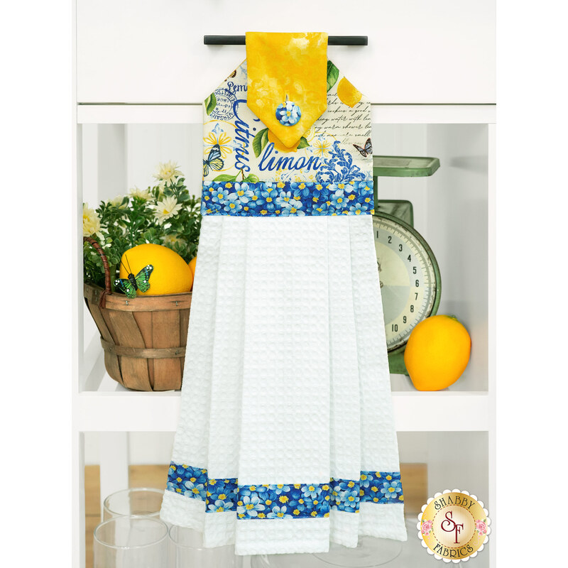 The completed Hanging Towel colored in blue and yellow fabrics from the Limoncello collection, staged on a kitchen drawer with coordinating decor.