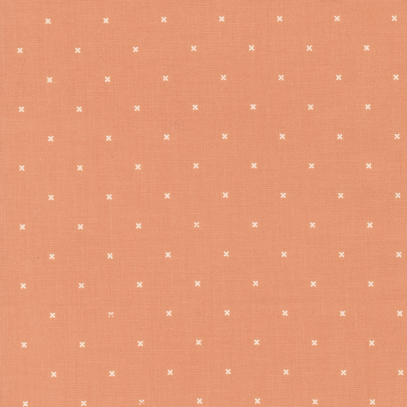 Light coral orange fabric with small x's that resemble cross stitching.