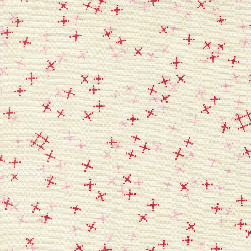 Light cream fabric with tossed light pink and red crosses and pound signs.