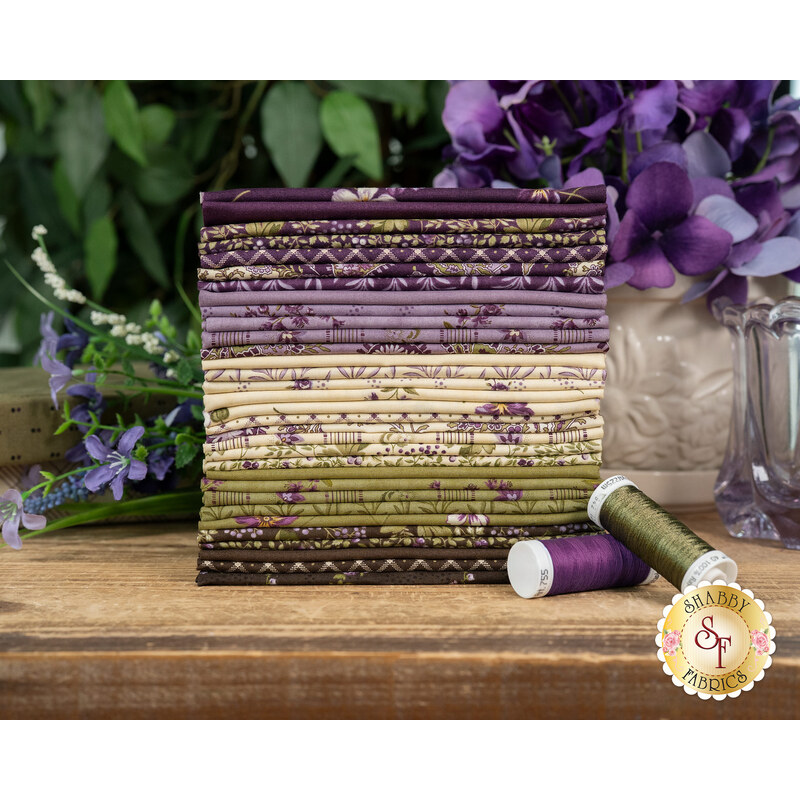A stack of the floral fabrics inclusded in the Collections for a Cause Essence FQ set, with flowers and a vase and thread