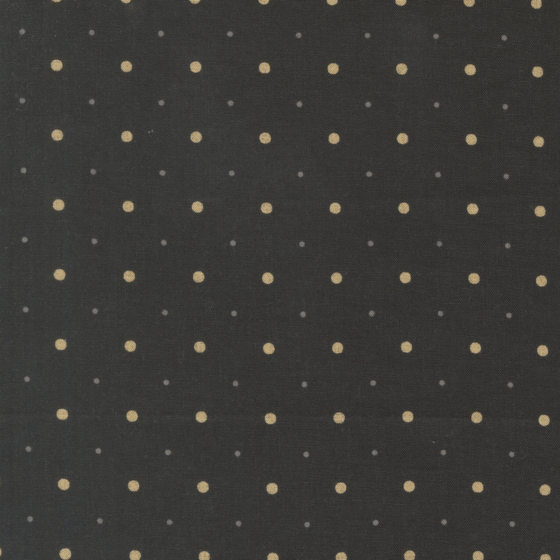 A black fabric with small and medium sized tan and tonal gray polka dots.