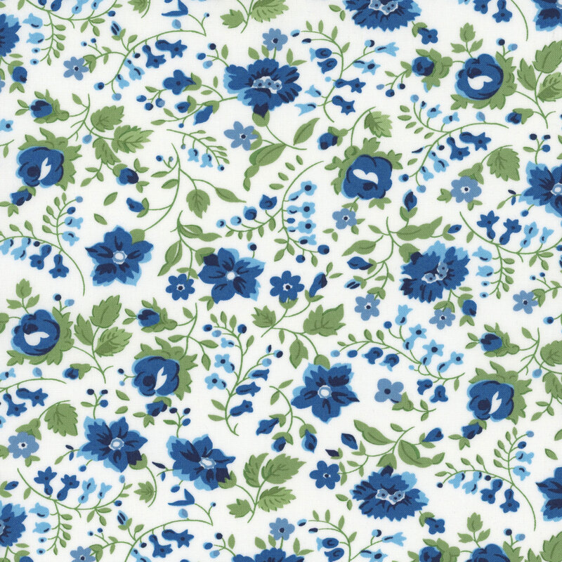 White fabric with blue florals and sprawling green leaves and stems.