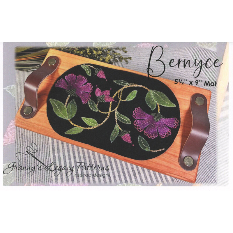 A floral embroidered design on a black mat, framed by a wooden holder with leather handles.