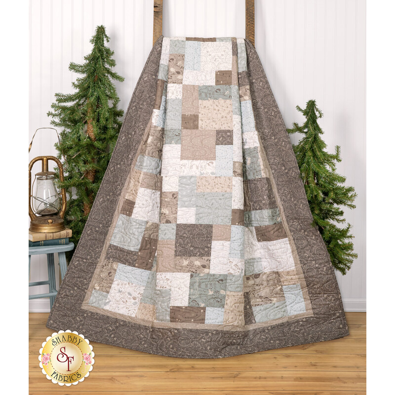 The Easy as ABC and 123 Quilt - Forest Tales quilt featuring a patchwork design in neutral tones hanging from a wooden ladder next to green trees and coordinating decor.