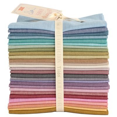 A stack of folded fabric in various colors, neatly tied with a ribbon label.