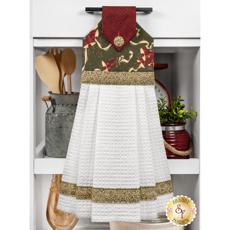 The completed Hanging Towel colored in green, cream, and red fabrics from the A Vintage Christmas collection, staged on a kitchen drawer with coordinating decor.