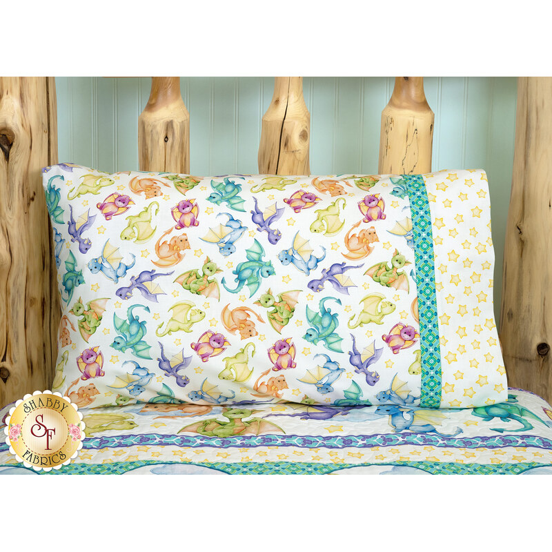The completed Magic Pillowcase colored in vibrant prints from the Dragon Friends collection by In The Beginning Fabrics, staged on a log bed with a coordinating bed quilt.