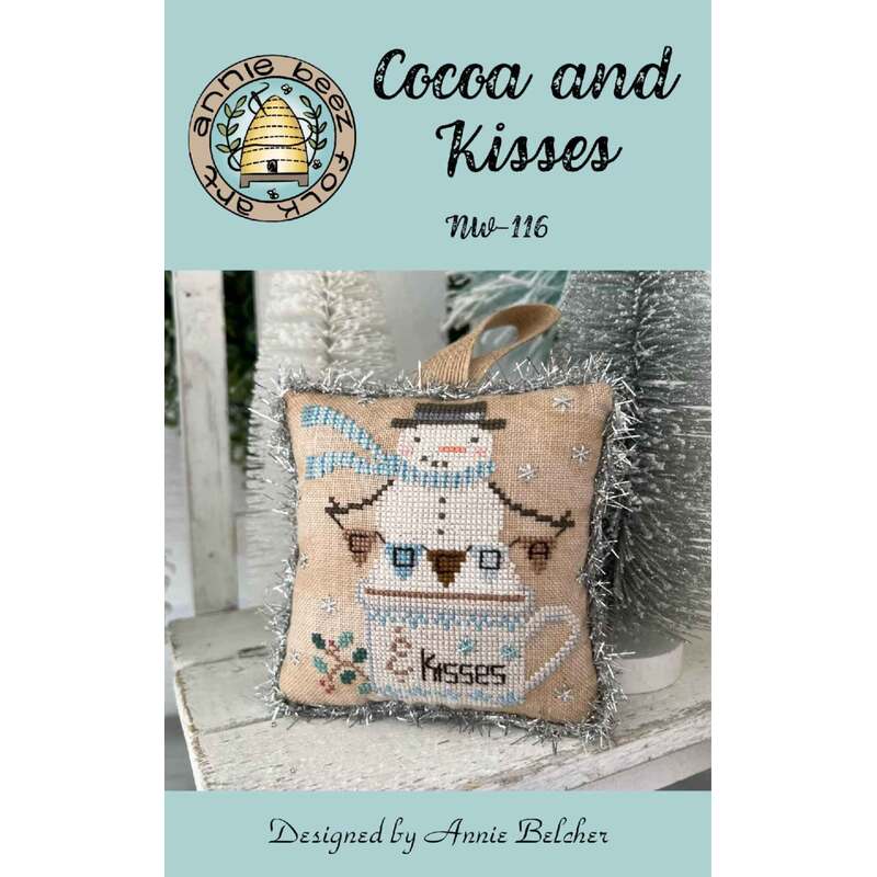 Cross-stitch pattern cover showing a small pillow with a bee and the words “Cocoa and Kisses.”