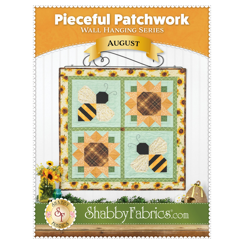 Front cover of the Pieceful Patchwork - August pattern featuring the completed sunflower and bee-themed wall hanging staged on a white wall with coordinating decor and yellow banners.