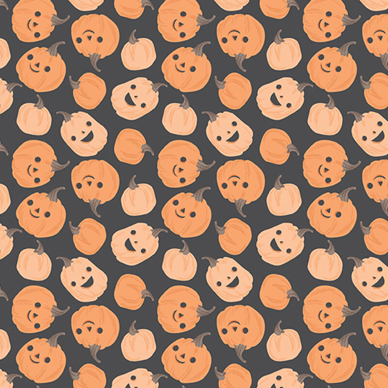 This dark gray fabric features scattered playful pumpkins with smiling jack-o’-lantern faces.