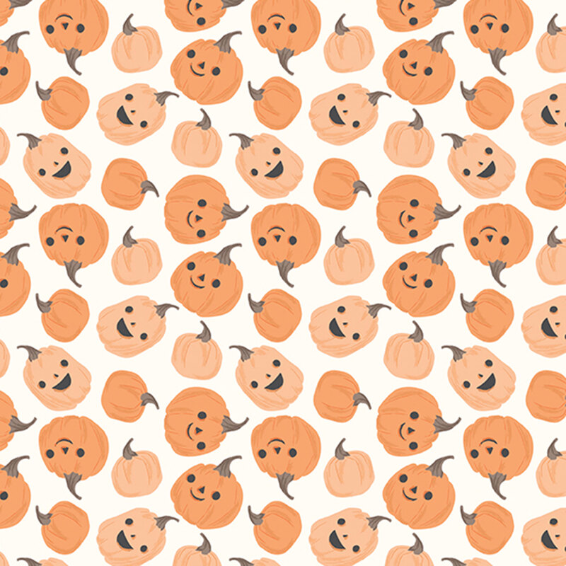 This white fabric features scattered playful pumpkins with smiling jack-o’-lantern faces.