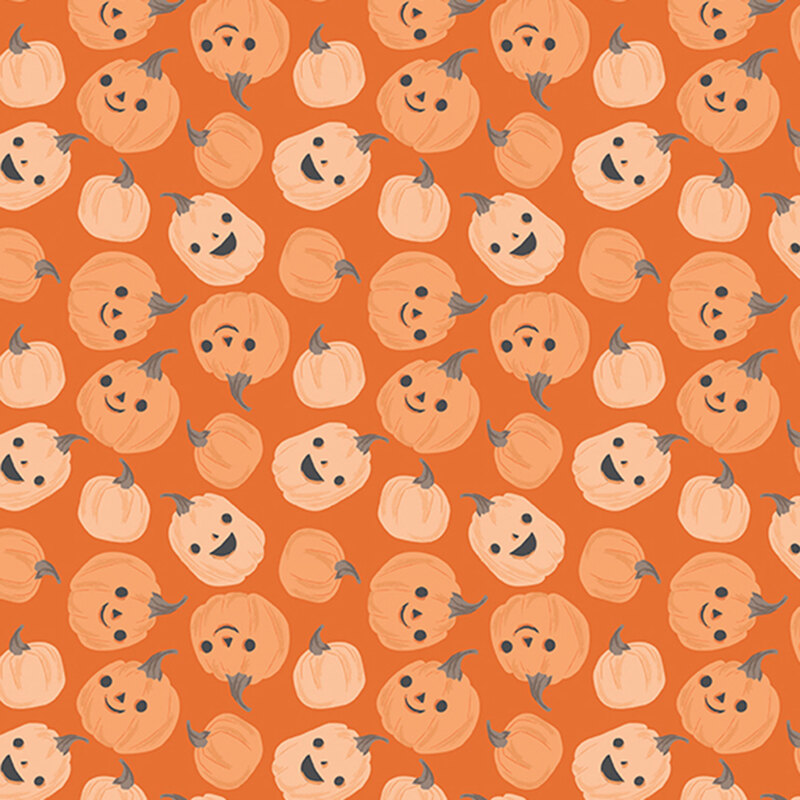 This orange fabric features scattered playful pumpkins with smiling jack-o’-lantern faces.