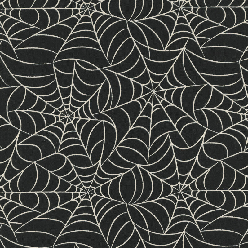 This black fabric features an intricate pattern of glow in the dark spiderwebs.