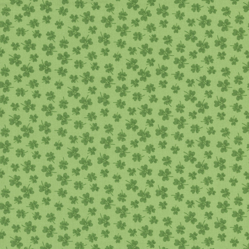 green clovers in various sizes scattered on mint green fabric
