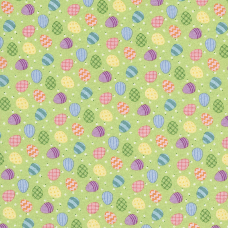 colorful easter eggs and white daisies scattered on pastel green fabric