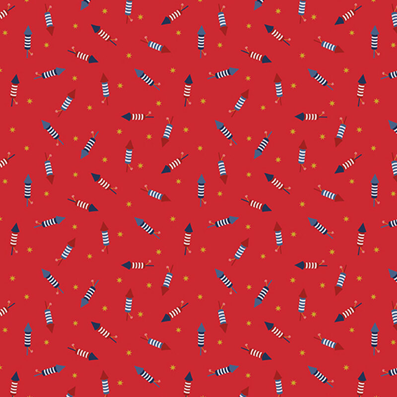 cherry red fabric tossed with bottle rockets in red, white and blue amongst yellow stars