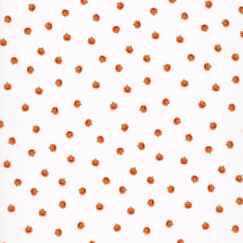 orange carved pumpkin heads scattered on white fabric