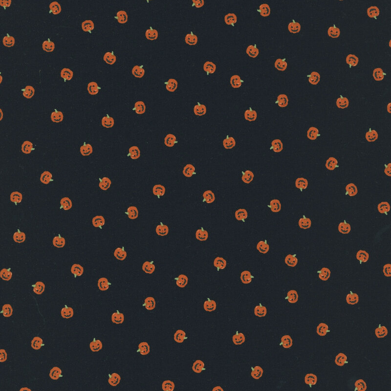 orange carved pumpkin heads scattered on black fabric