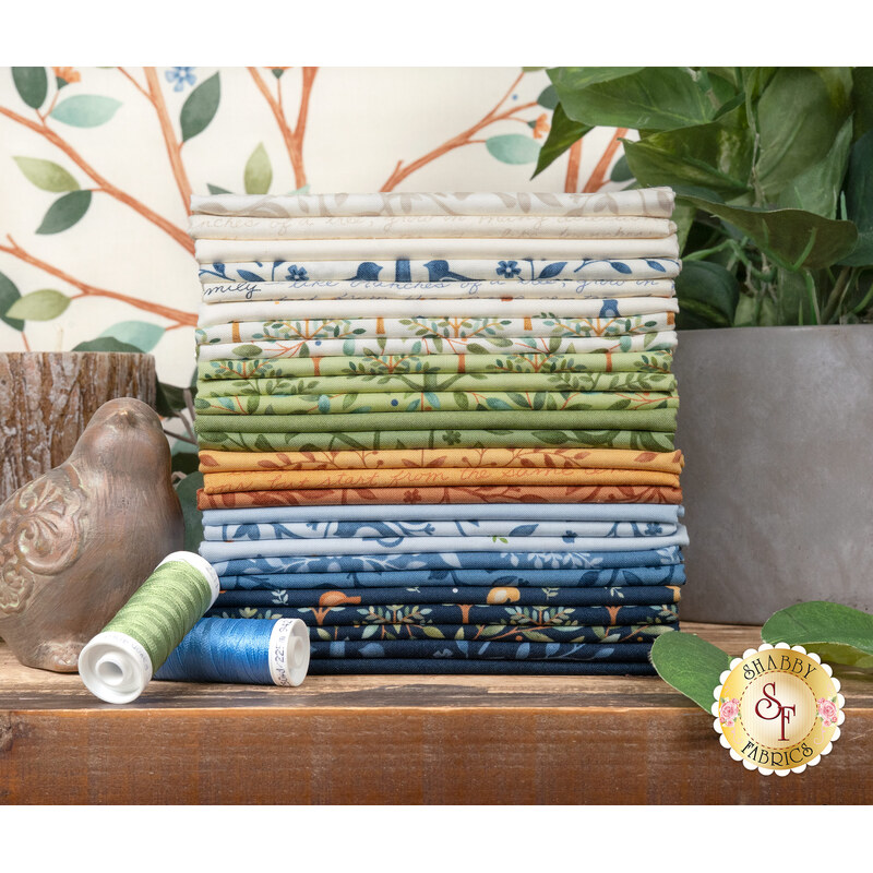A stack of the fabrics featured in the Family Tree fq set, with plants and a candle and a bird and thread.