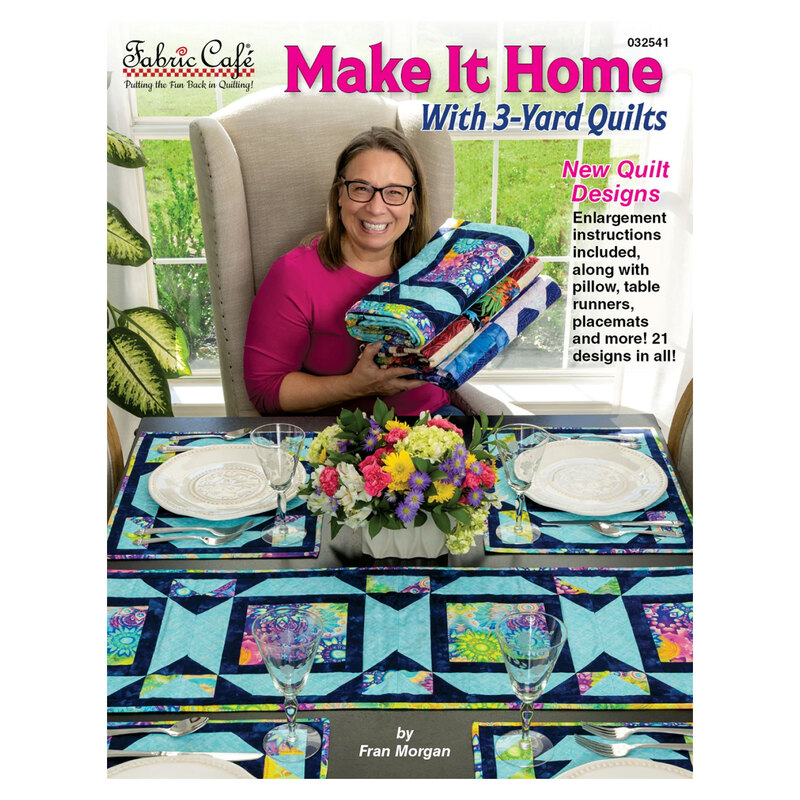 The front of the Make It Home With 3-Yard Quilts book, featuring Fran Morgan holding up a stack of folded quilts with coordinating table runners and placemats set on a dining table in front of her.
