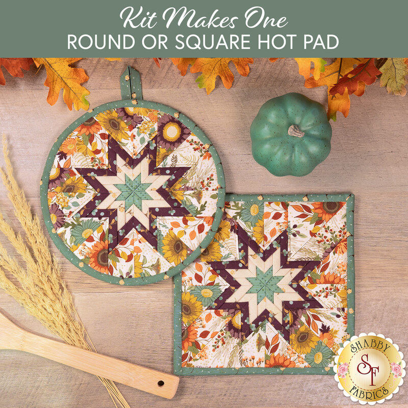 The two completed cream Folded Star Hot Pads, one round and one square, slightly overlapping each other and staged on a wooden table with coordinating autumnal-themed décor and cooking ware.