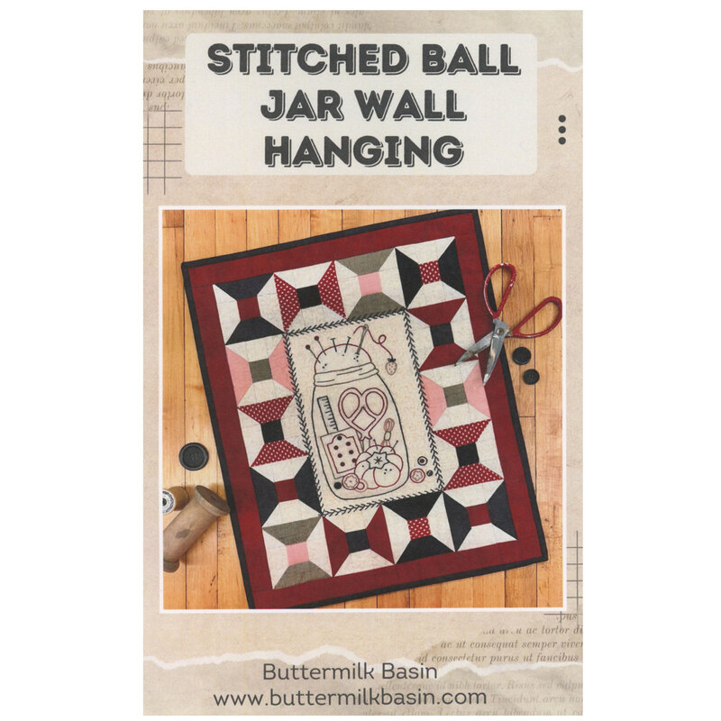 The front cover showing an showing the completed wall hanging pattern of a ball jar filled with sewing tools with a border of thread spools.