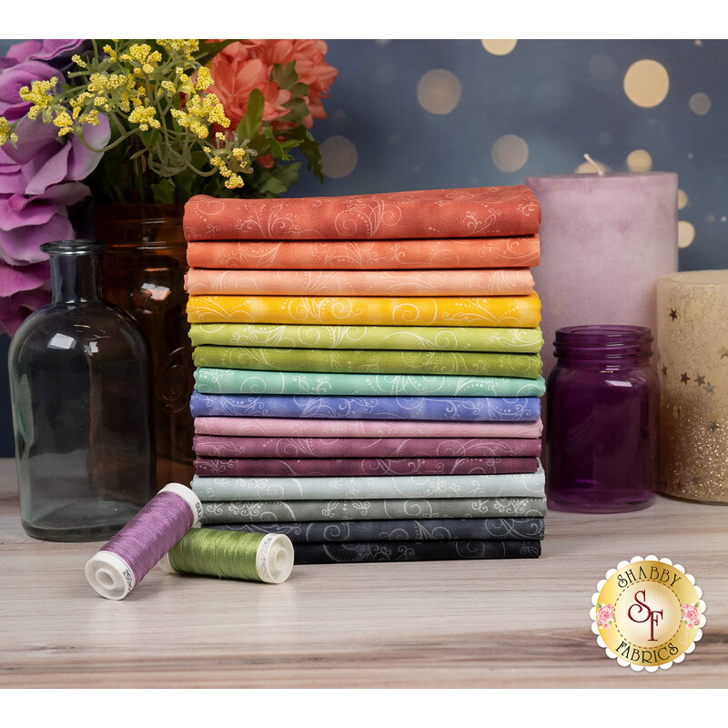 A stack of the fabrics included in the Equinox - Elegant collection, with flowers and mason jars and candles and thread.