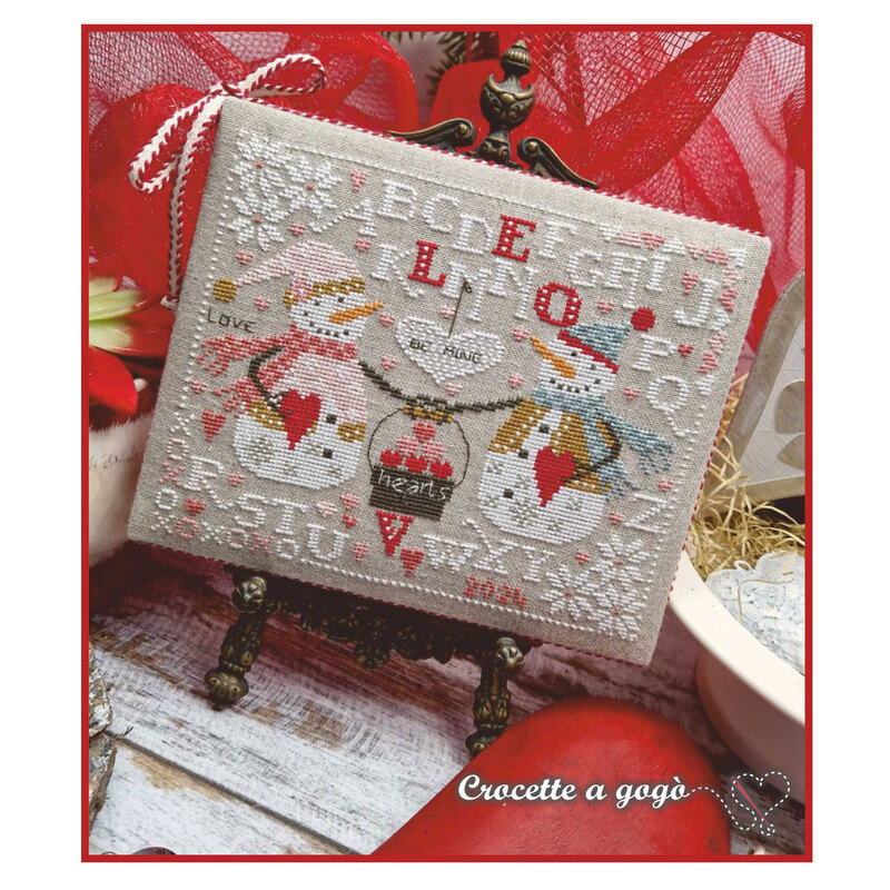 A image of the completed Two Hearts cross stitch pattern staged with red tulle. 