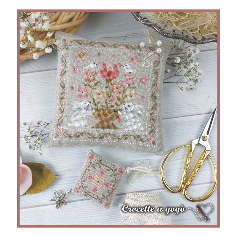 A image of the completed Spring Basket cross stitch pattern staged with baby's breath and scissors. 