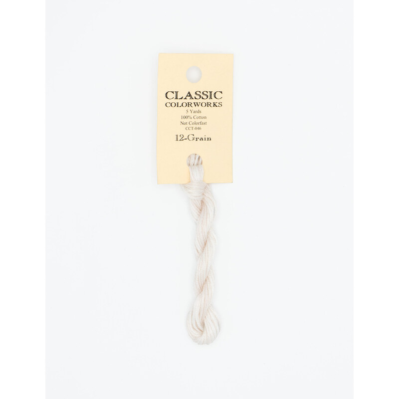 A skein of white embroidery floss, twisted and bundled, with a cream and black label featuring the brand name and color information.