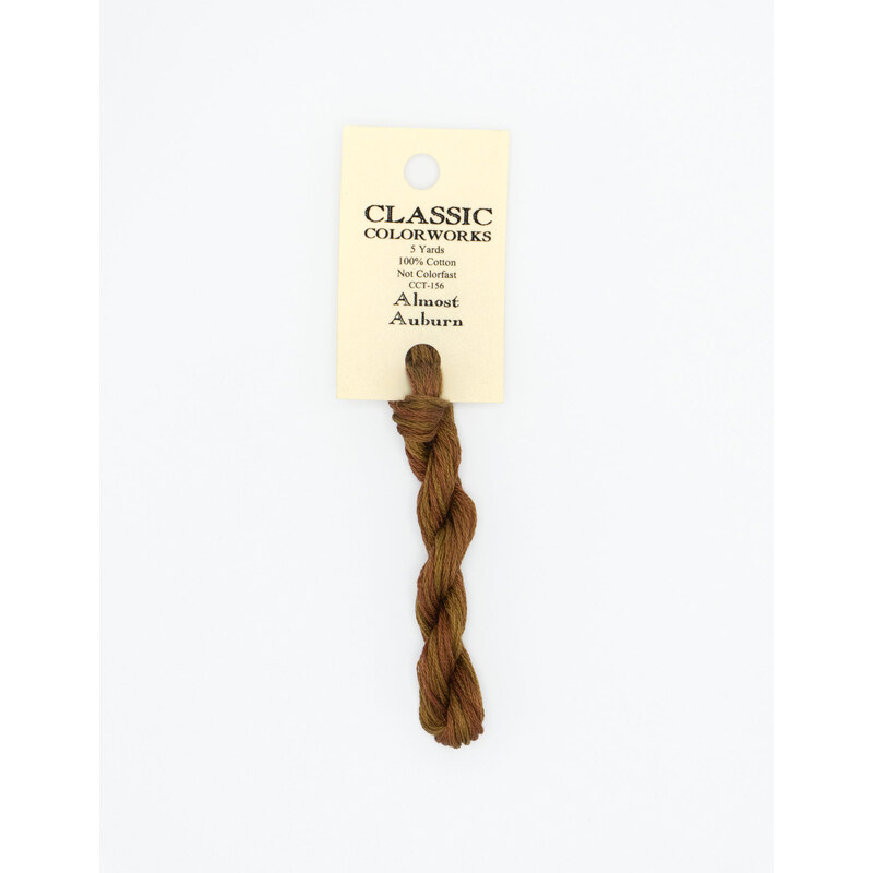 A skein of auburn red embroidery floss, twisted and bundled, with a cream and black label featuring the brand name and color information.