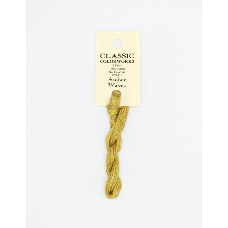 A skein of gold embroidery floss, twisted and bundled, with a cream and black label featuring the brand name and color information.
