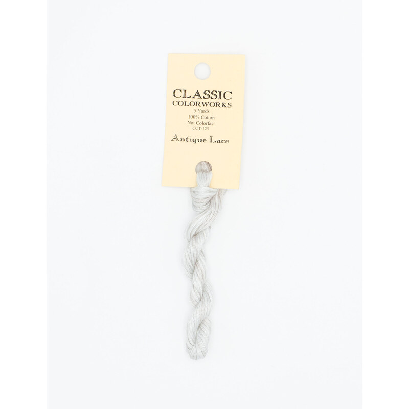 A skein of white embroidery floss, twisted and bundled, with a cream and black label featuring the brand name and color information.