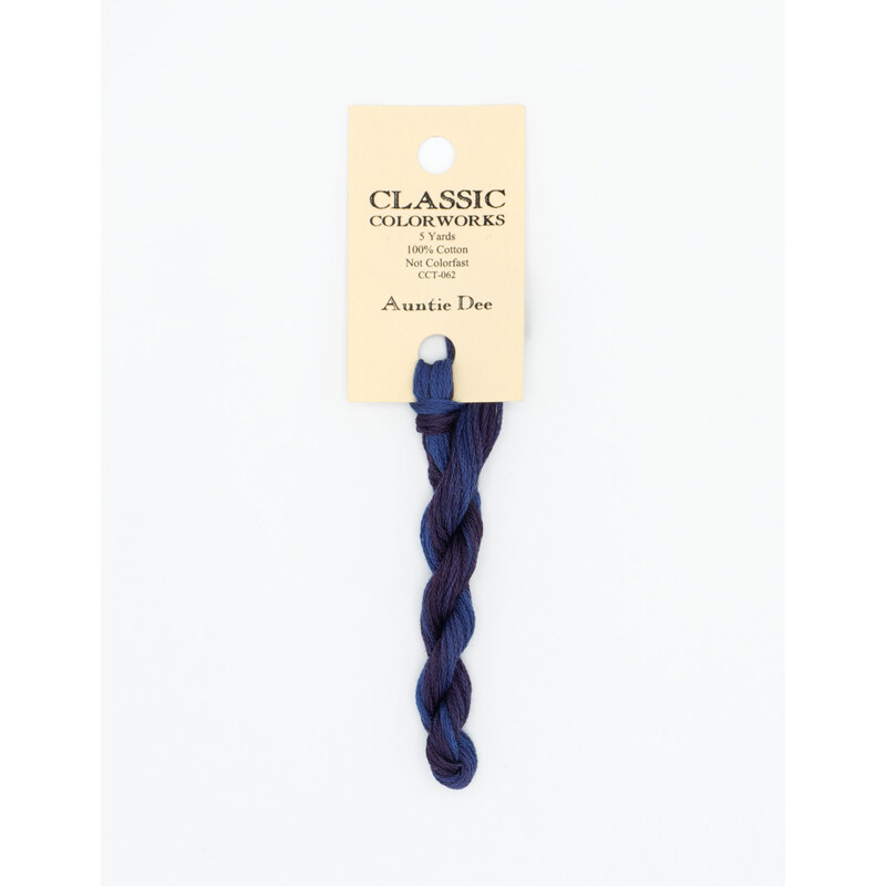 A skein of variegated dark blue and dark purple embroidery floss, twisted and bundled, with a cream and black label featuring the brand name and color information.