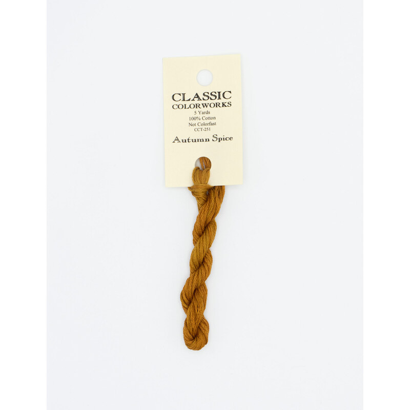 A skein of burnt orange embroidery floss, twisted and bundled, with a cream and black label featuring the brand name and color information.