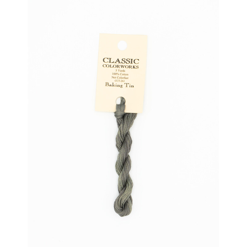 A skein of gray embroidery floss, twisted and bundled, with a cream and black label featuring the brand name and color information.