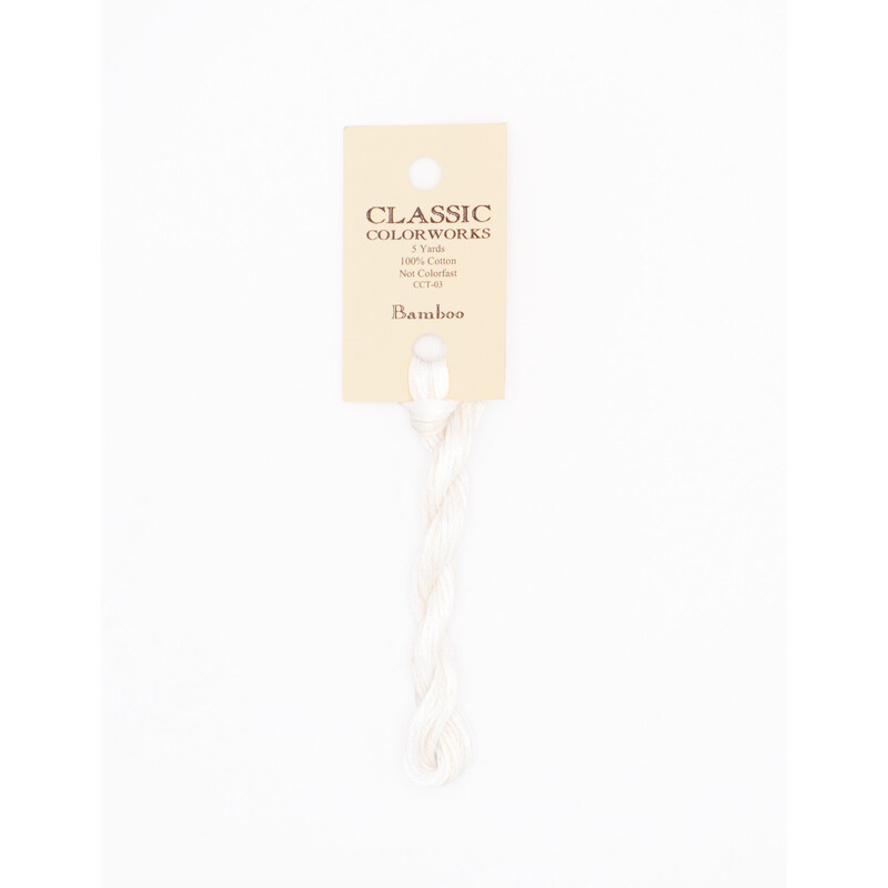 A skein of white embroidery floss, twisted and bundled, with a cream and black label featuring the brand name and color information.