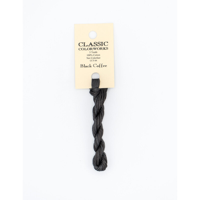 A skein of soft black embroidery floss, twisted and bundled, with a cream and black label featuring the brand name and color information.