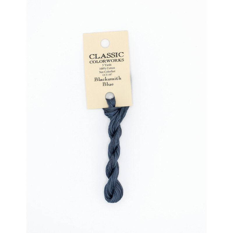 A skein of midnight blue embroidery floss, twisted and bundled, with a cream and black label featuring the brand name and color information.
